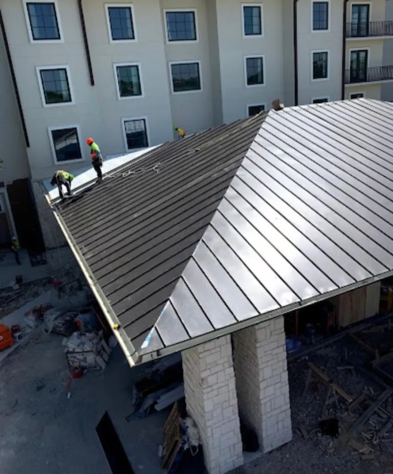 Crew installing standing seam metal roof panels on a commercial project in Fort Lewis